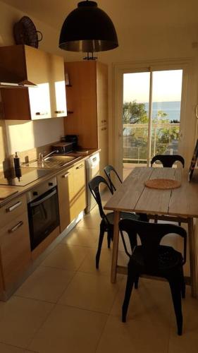 une cuisine avec une table et des chaises en bois ainsi qu'une fenêtre dans l'établissement La Mer Veille, à Cerbère