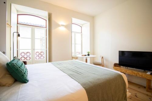 a bedroom with a large bed and a flat screen tv at Casas do Pátio in Coimbra