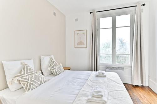 une chambre blanche avec un grand lit et une fenêtre dans l'établissement Appartement Cosy Vue sur Paris Bois de Boulogne, à Puteaux