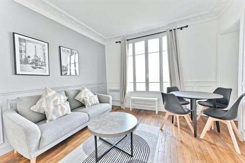 un salon avec un canapé, une table et des chaises dans l'établissement Appartement Cosy Vue sur Paris Bois de Boulogne, à Puteaux