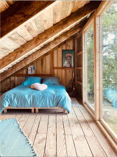 - une chambre avec un lit dans une maison en bois dans l'établissement La Cabane, à Prailles