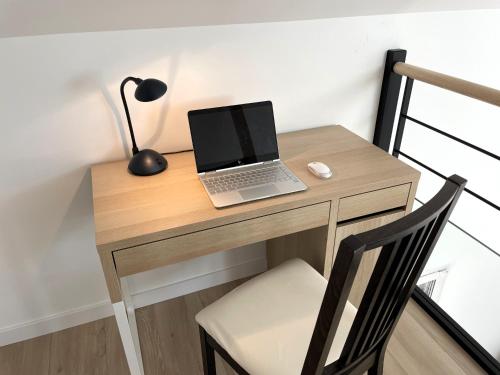 un ordinateur portable assis sur un bureau en bois avec une chaise dans l'établissement Maison indépendante au calme, à Thorigné-sur-Vilaine
