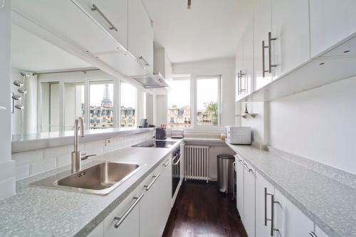 La cuisine est équipée de placards blancs et d'un évier en acier inoxydable. dans l'établissement Eiffel, à Paris
