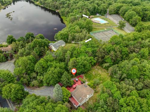 eine Luftaufnahme eines Hauses im Wald neben einem See in der Unterkunft Cozy cottage in the heart of pocono in Long Pond