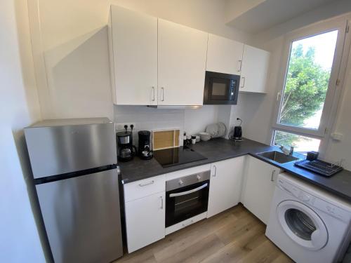 une cuisine avec des armoires blanches et un réfrigérateur en acier inoxydable dans l'établissement Appartement renove apercu mer remblai, à Les Sables-dʼOlonne