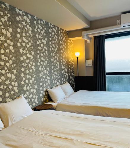two beds in a hotel room with floral wallpaper at Kyoto Sanjo Ohashi in Kyoto