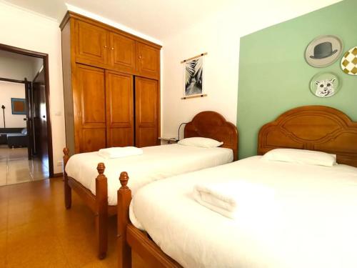 a bedroom with two beds and a wooden cabinet at Mountain View Beach House in Costa da Caparica