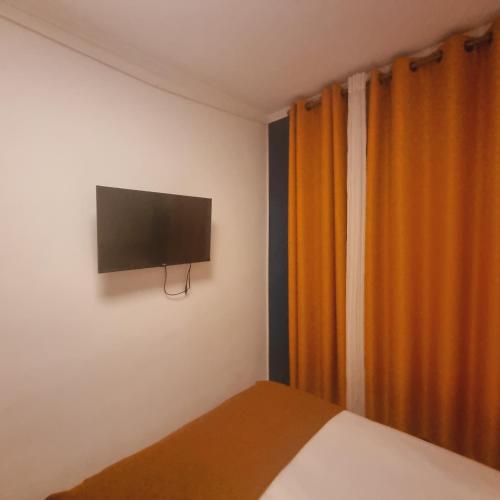 une chambre avec un lit et une télévision à écran plat au mur dans l'établissement Joli studio à Bastille, à Paris