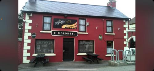 a red building with two benches outside of it at Riverside cabin in Limerick