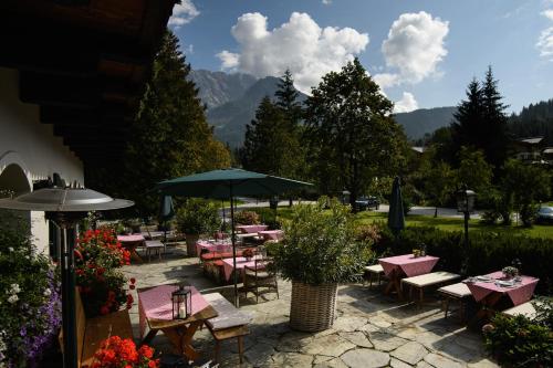 a patio with tables and chairs and an umbrella at House of Hütter - Wachtelhof & SPA in Maria Alm am Steinernen Meer