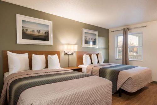 a hotel room with two beds and two windows at Birch Hill Suites Kansas City - Independence in Independence