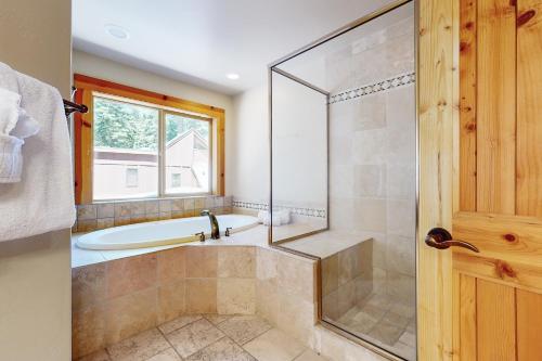 a bathroom with a tub and a shower with a glass door at Wooded Luxury at Tahoe Donner in Truckee
