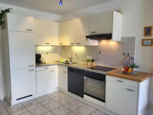 a white kitchen with white cabinets and a sink at Apartment Lakeview La Marea by Interhome in Piazzogna