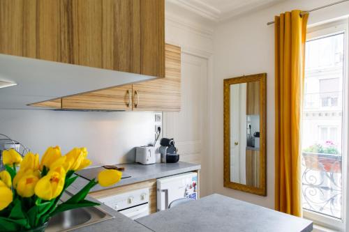 une cuisine avec des fleurs jaunes dans un vase sur un comptoir dans l'établissement Radiant 1BD Apart in Clignancourt, à Paris