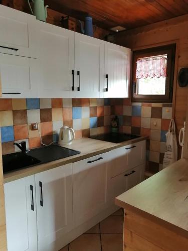 une cuisine avec des armoires blanches, un évier et une fenêtre dans l'établissement appartement sur domaine des Sybelles St Jean d'Arves, à La Chal