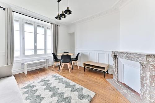 un salon blanc avec une table et des chaises dans l'établissement Appartement Vue sur Tour effeil Defense, à Puteaux