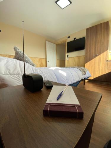 a bedroom with a bed and a desk with a pen on it at Cabaña de Lujo en Llau Llao, con agua purificada, confort y bienestar con especial cuidado ambiental, hermosa vista, estratégicamente ubicada entre Castro y Dalcahue in Tentén