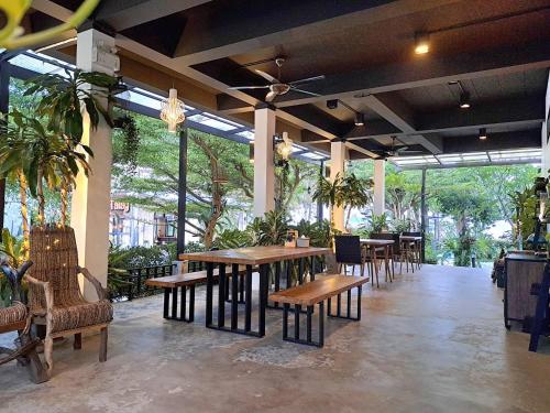 a restaurant with wooden tables and chairs and plants at Magic House - No Pets Allowed in Chumphon