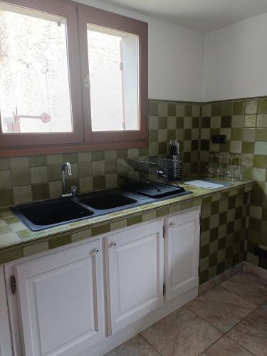 - une cuisine avec des placards blancs, un évier et 2 fenêtres dans l'établissement LE GRAND CASTILLON - Gîte pêche avec 2 étangs privés, foret et Jacuzzi en option, à Castelnau-dʼAuzan