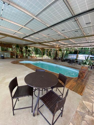 a pool with a table and chairs next to a swimming pool at Pousada Paraíso das Águas in Itirapina
