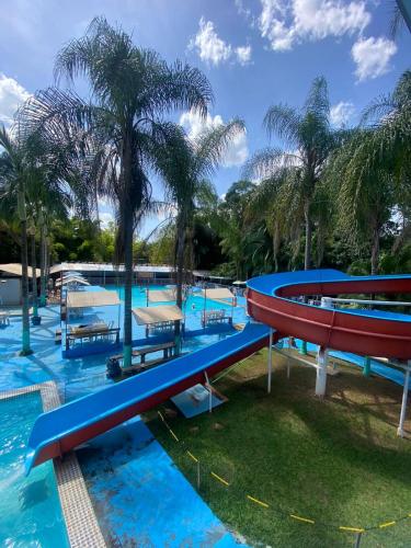 a pool with a slide at a resort with palm trees at Pousada Paraíso das Águas in Itirapina