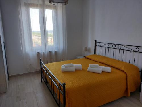 a bedroom with a yellow bed with two towels on it at A Casa di Enrichetta in Montalcino