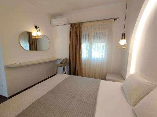 a bedroom with a bed and a mirror and a window at Nostos in Patitiri