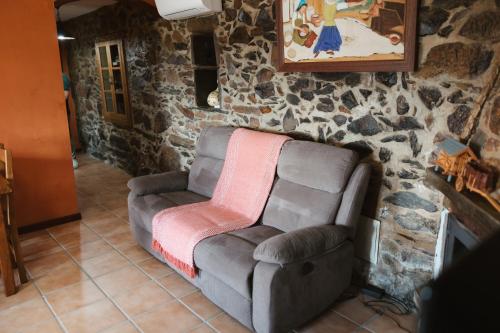 a couch in a room with a stone wall at Quinta da Malhada in Cabril