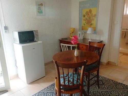 a dining room with a table and a microwave at Charmant F1 indépendant rez de jardin proche de vichy petits dej compris in Bellerive-sur-Allier