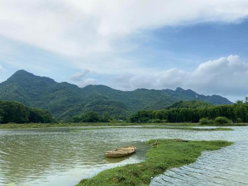 a boat on a river with mountains in the background at Charm Vân Long in Ninh Binh