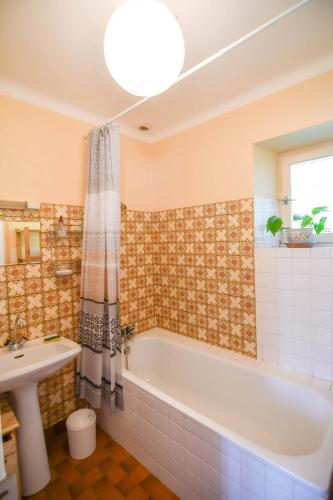 une salle de bain avec une baignoire et un lavabo dans l'établissement La Maison Bleue, à Lanfains