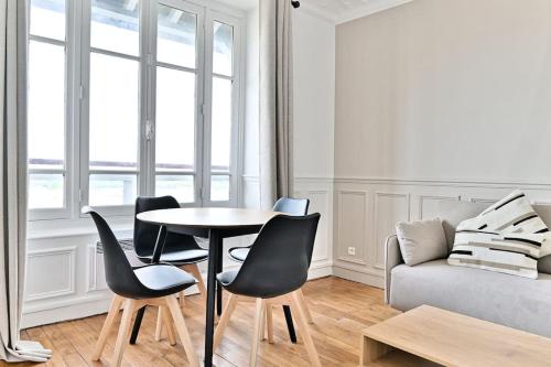 un salon avec une table, des chaises et un canapé dans l'établissement Appartement Spacieux Vue sur Paris Boulogne, à Puteaux