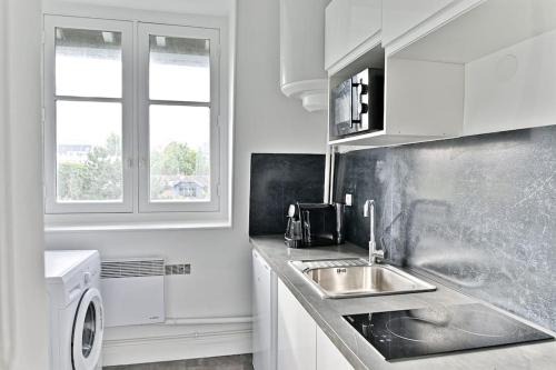 une cuisine avec un évier et une machine à laver dans l'établissement Appartement Spacieux Vue sur Paris Boulogne, à Puteaux