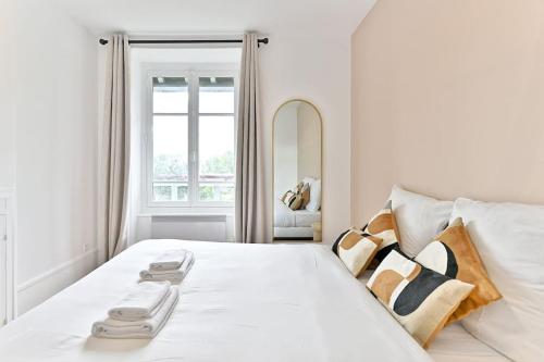 une chambre avec un lit blanc avec des oreillers et une fenêtre dans l'établissement Appartement Spacieux Vue sur Paris Boulogne, à Puteaux