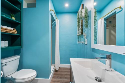 a blue bathroom with a toilet and a sink at Eccentric home with pool tiki hut & outdoor kitchen in Pompano Beach
