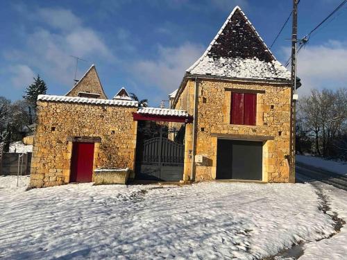 un bâtiment en briques avec des portes rouges dans la neige dans l'établissement Le Clos de Peyruzel, Daglan, à Daglan