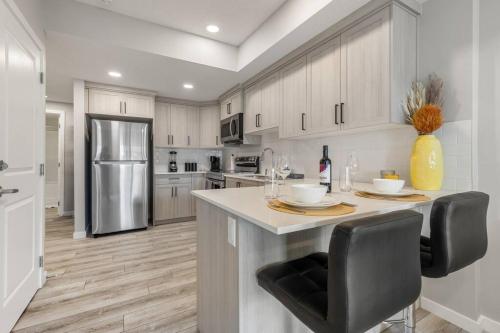 a kitchen with a counter with chairs and a refrigerator at Brand New Luxury Walk-out Suite - Calgary in Calgary