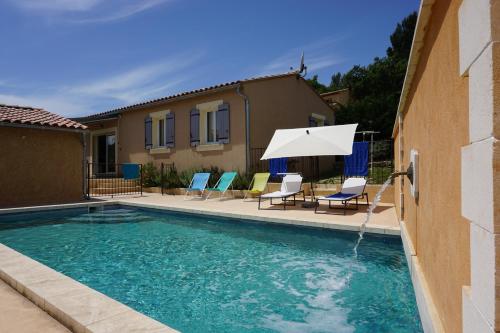 une piscine avec des chaises et un parasol à côté d'une maison dans l'établissement Dodo au Luberon, à Villars