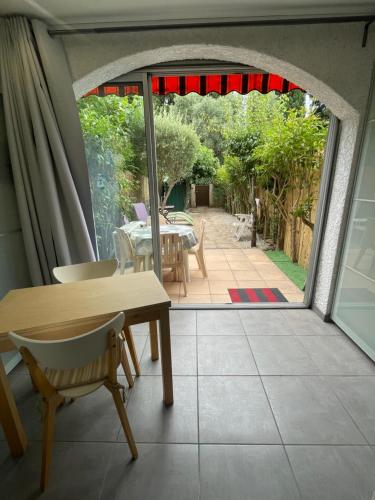 Une porte ouverte s'ouvre sur une terrasse avec une table et des chaises. dans l'établissement Charmant Studio, à La Londe-les-Maures