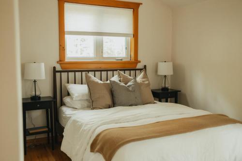 a bedroom with a bed with pillows and a window at The Doma Lodge - Cozy Muskoka Cabin in the Woods in Huntsville