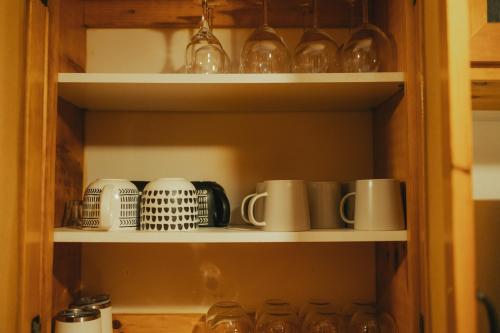 a cupboard filled with lots of cups and mugs at The Doma Lodge - Cozy Muskoka Cabin in the Woods in Huntsville