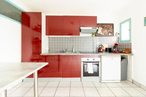 une cuisine avec des armoires rouges et un réfrigérateur blanc dans l'établissement les berges de l'Oust, à Malestroit