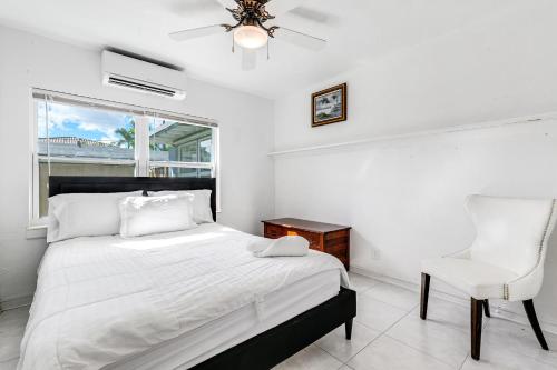 a bedroom with a bed and a chair and a window at Bungalow with large backyard 5 min from beach in Pompano Beach