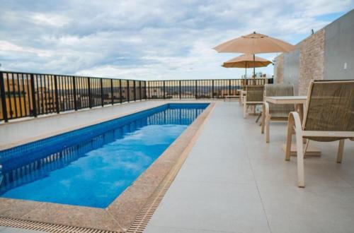 a swimming pool with chairs and an umbrella on a balcony at Charmoso Duplex ao Lado da Torre de TV Brasília in Torto