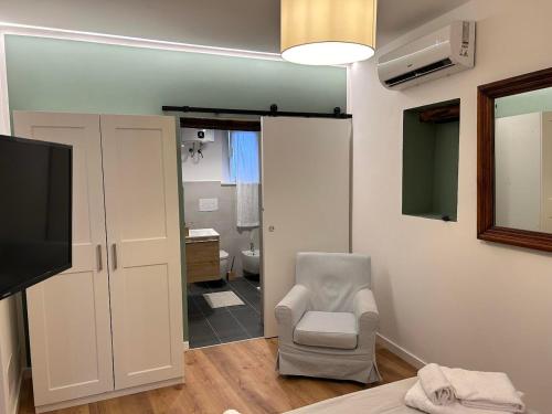 a room with a tv and a chair and a bathroom at Baglio San Giovanni in Palermo