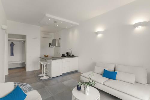 a white living room with a white couch and a kitchen at Alexander Suites in Drios