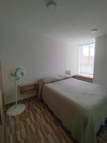 a bedroom with a bed and a window and a fan at Apartamento Ibagué in Ibagué