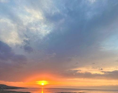 a sunset over the ocean with the sun in the sky at Ethnocomplex Aikol in Tong