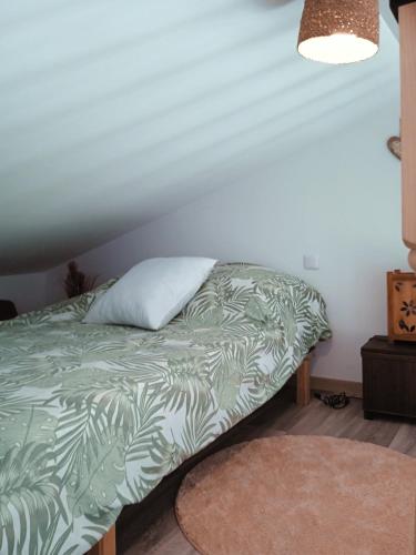 - un lit avec une couverture verte et un oreiller dans l'établissement La Salamandre, à Saint-Côme-de-Fresné