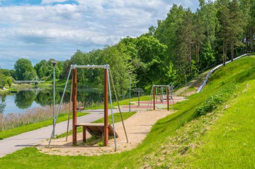 a park with a row of swings and a bench at Molėtai Hotel in Molėtai